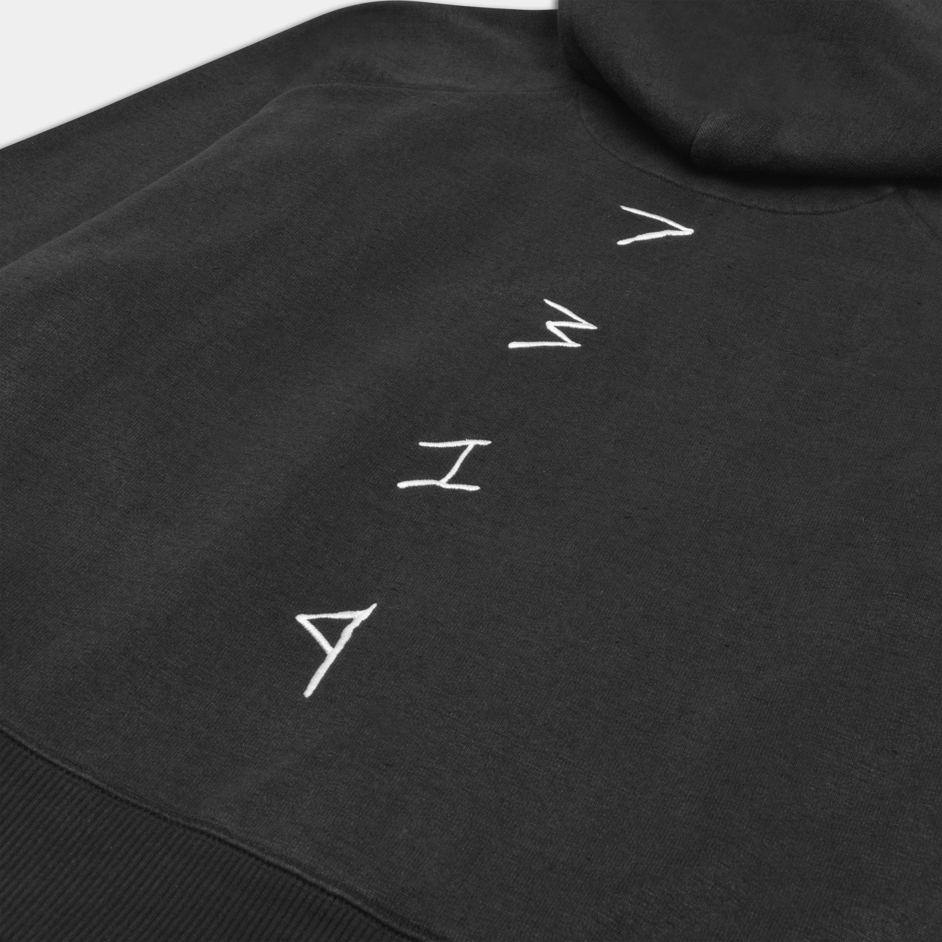 black hemp hoodie. Close up shot of white embroidered 7319 detailing down spine. Hemp active wear. Conscious zero waste fashion.